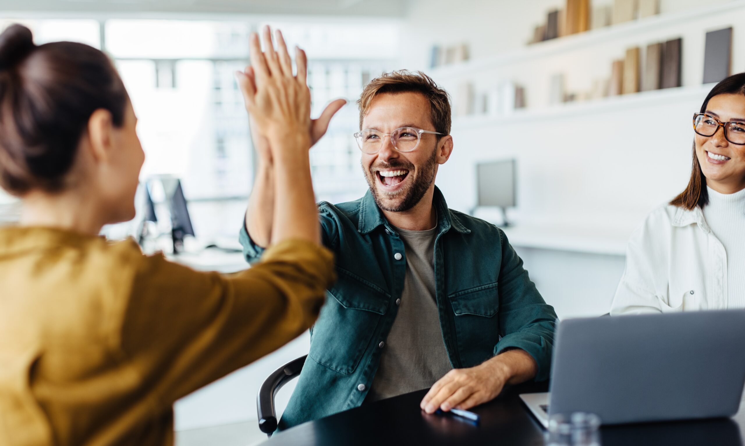 Two people high fiving at work.