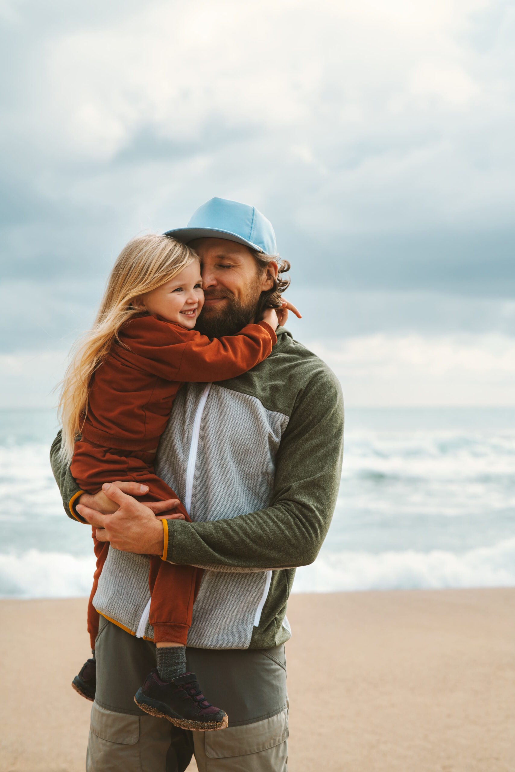 Dad holding young girl on the beach.